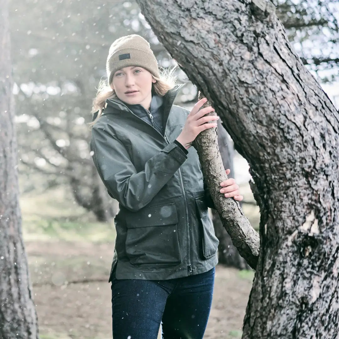 Person in a green Musto Womens Burnham Jacket 2.0 hugging a tree trunk outdoors