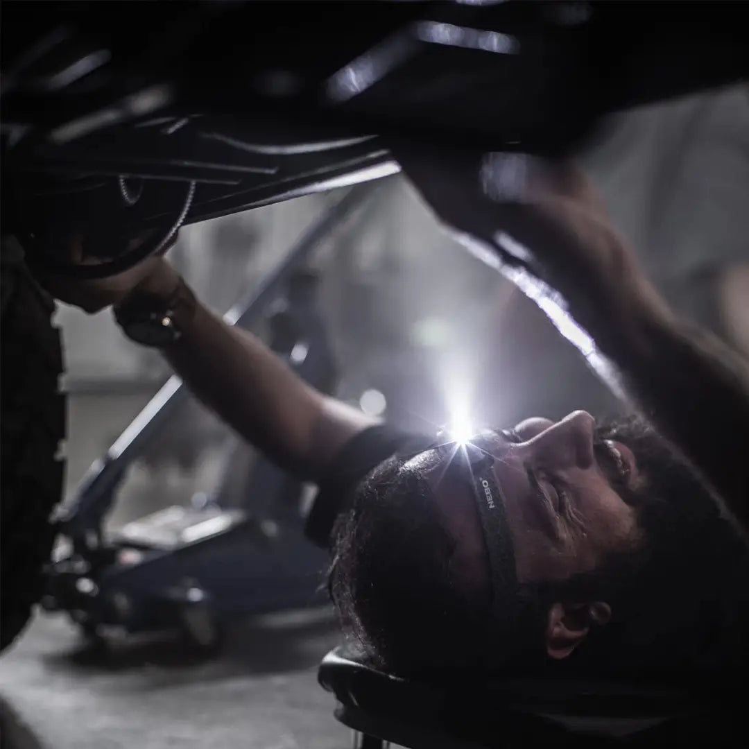 Person working under a vehicle with NEBO Mycro Headlamp, ideal for country clothing and hunting