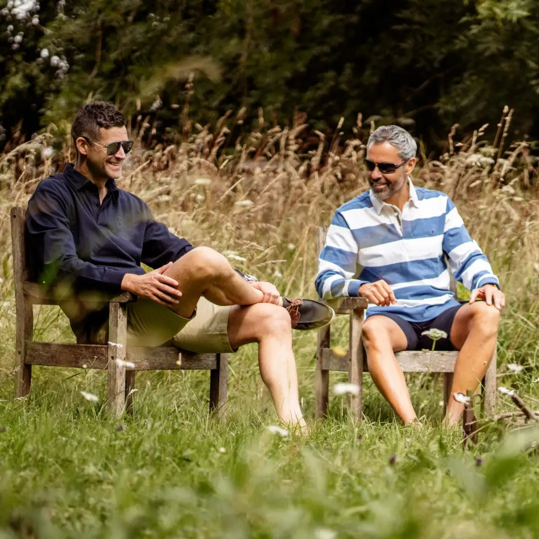 Two men in wooden chairs wearing stylish Forest Chino Shorts outdoors