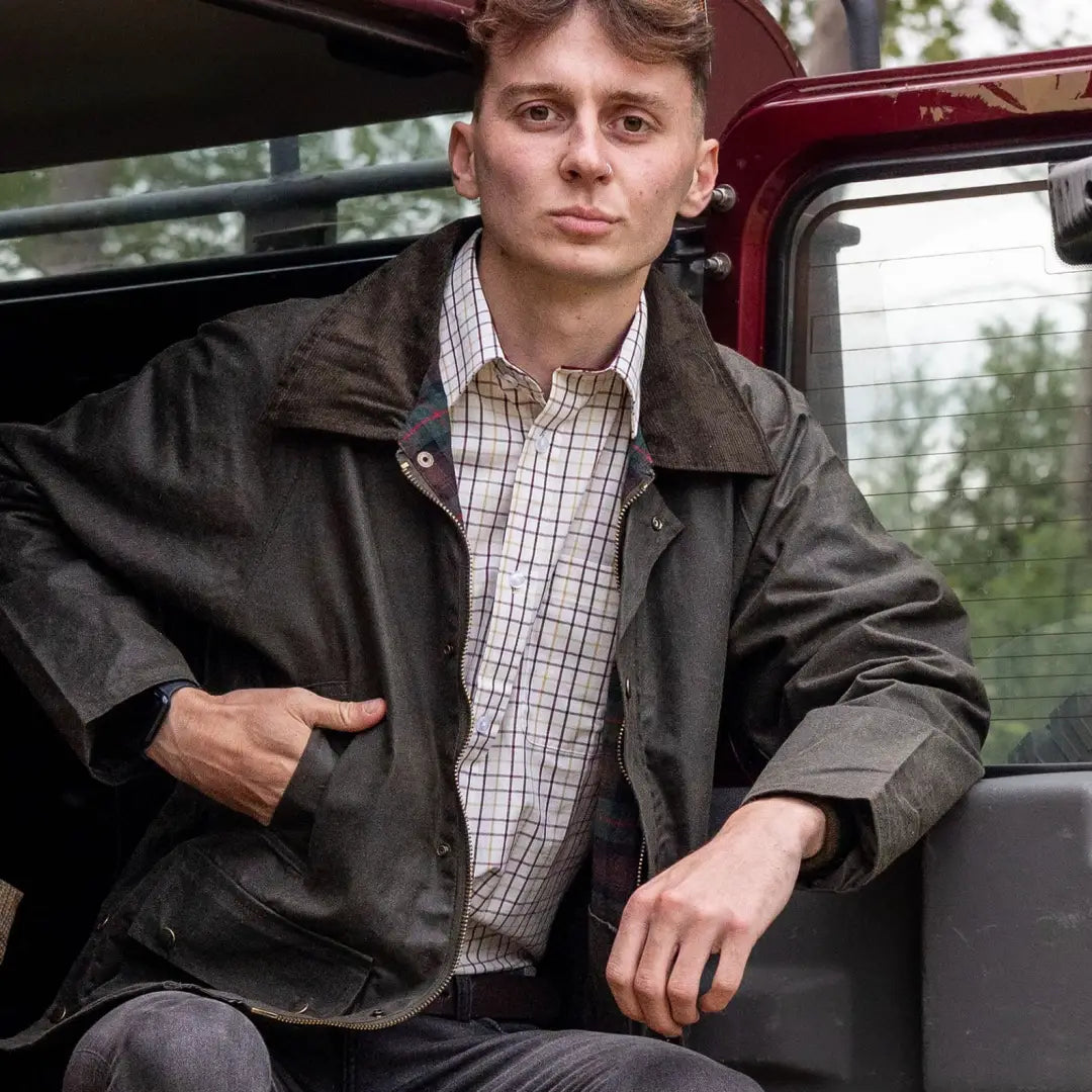 Young man in a leather jacket and plaid shirt showcasing a Mens Classic Antique Wax Jacket