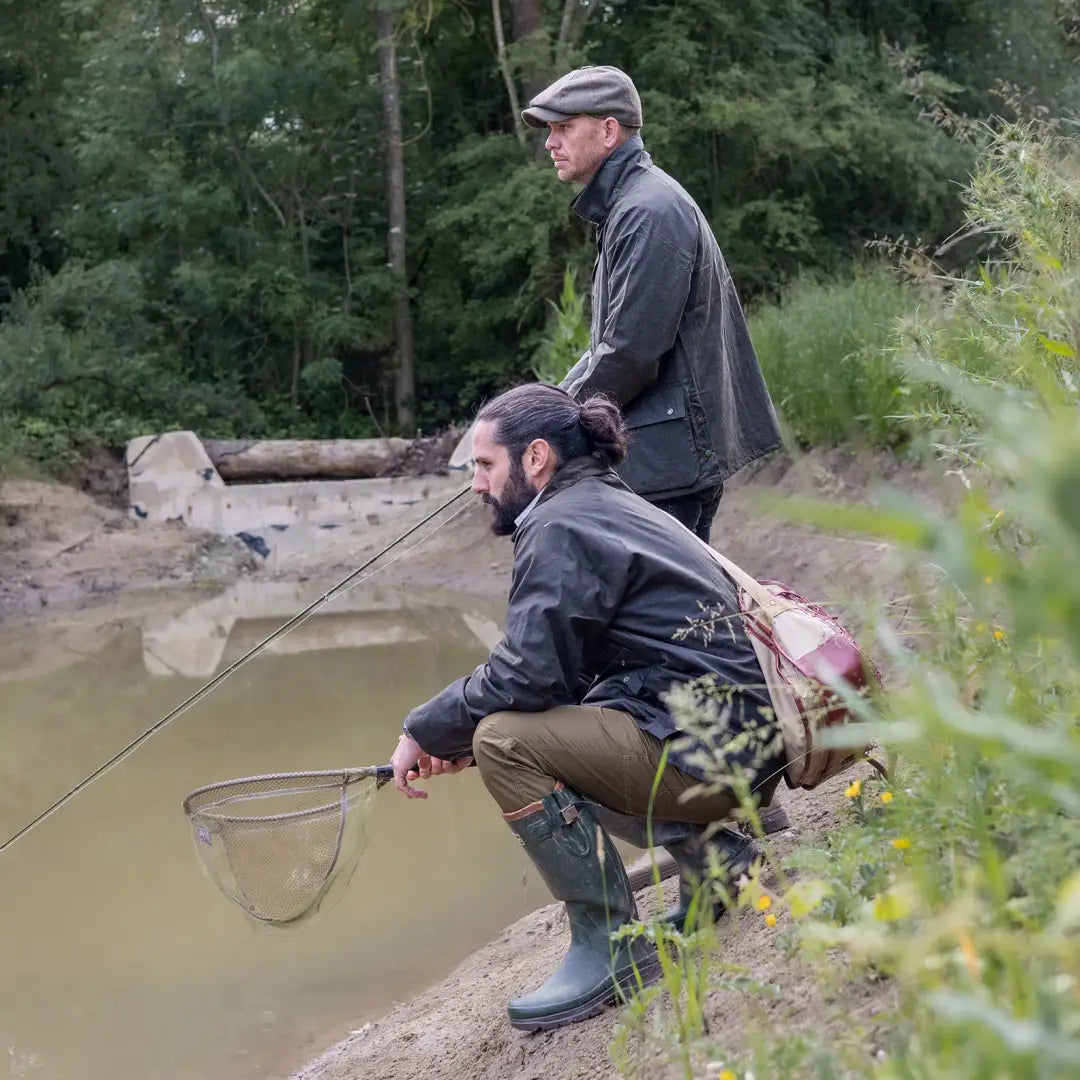 Two men fishing by a muddy pond wearing Mens Classic Antique Wax Jacket