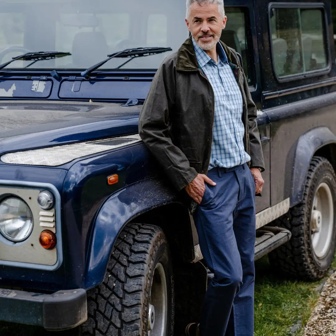 Land Rover Defender with a person in a Mens Classic Antique Wax Jacket outdoors