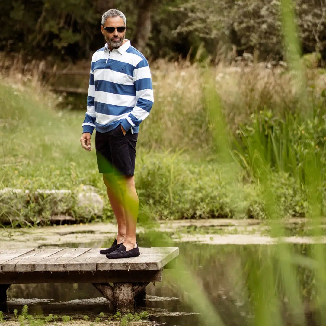 Man in a striped rugby shirt stands on a dock by a pond, showcasing Forest Classic Stripe