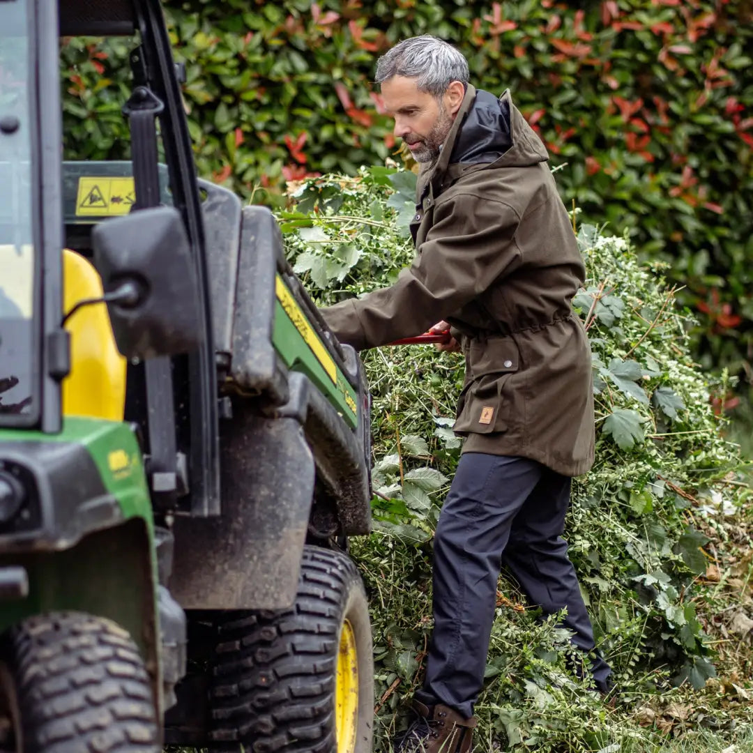 Person loading leafy plants into a yellow and green tractor by New Forest Country Sport Jacket