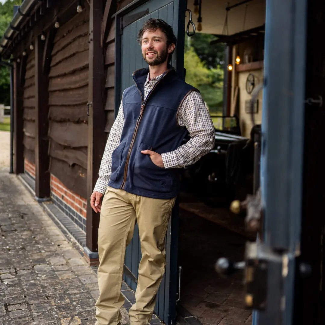 Man in a navy fleece gilet over a checkered shirt and khaki pants, styled casually