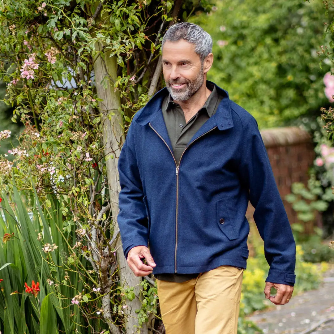 Middle-aged man in a blue New Forest Harrington Jacket walking outdoors in a garden