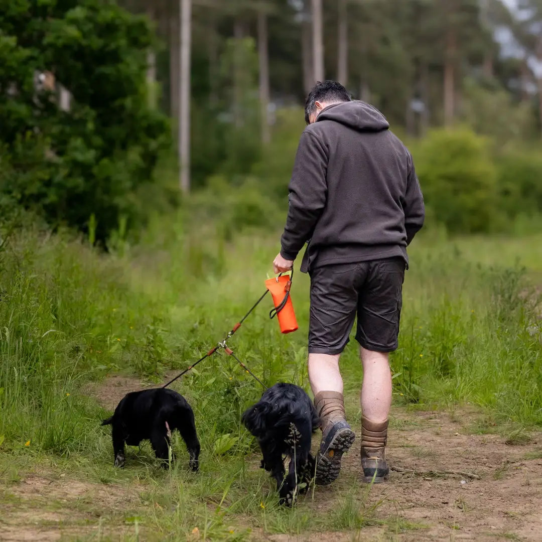 Person walking two black dogs on a dirt path while wearing a Forest Heathland Hoodie