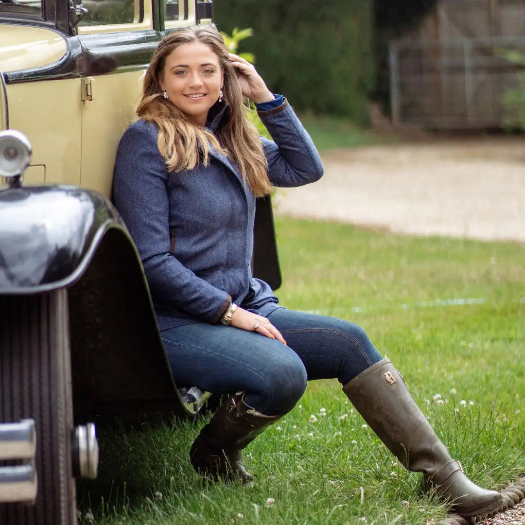 Young woman in a navy sweater by a vintage car wearing a Forest Jessica Tweed Field Coat