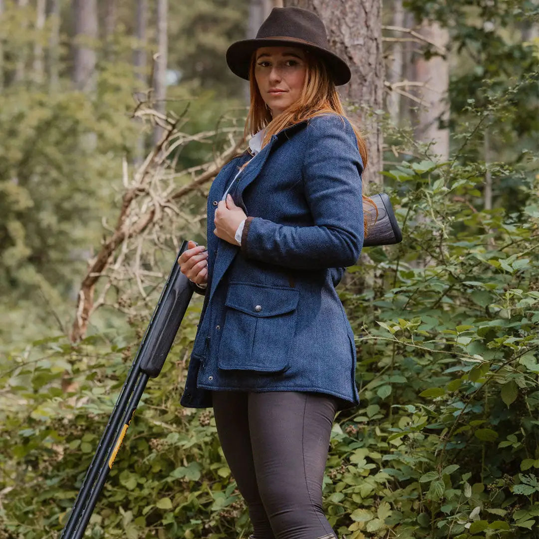 Woman in outdoor gear with a shotgun wearing the New Forest Jessica Tweed Field Coat