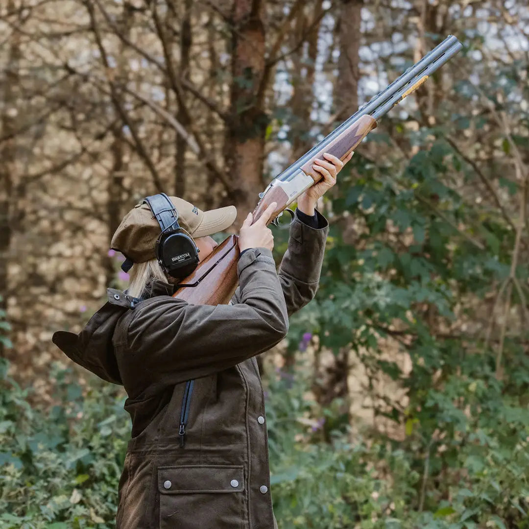 Person in a brown jacket aiming a shotgun, showcasing the New Forest Ladies Country Sport Jacket