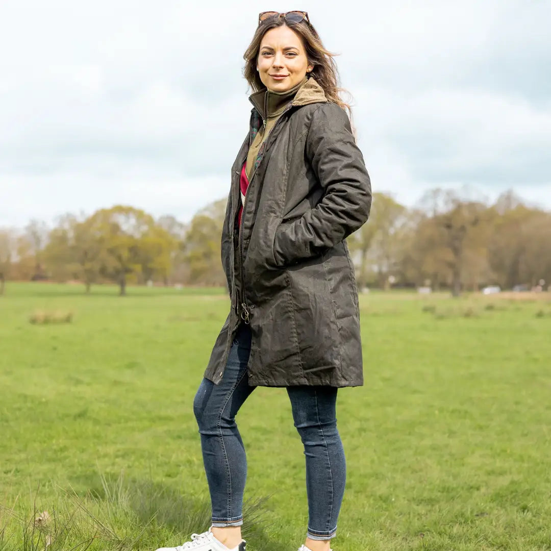 Woman in long olive green wax jacket and jeans enjoying the outdoors in country clothing