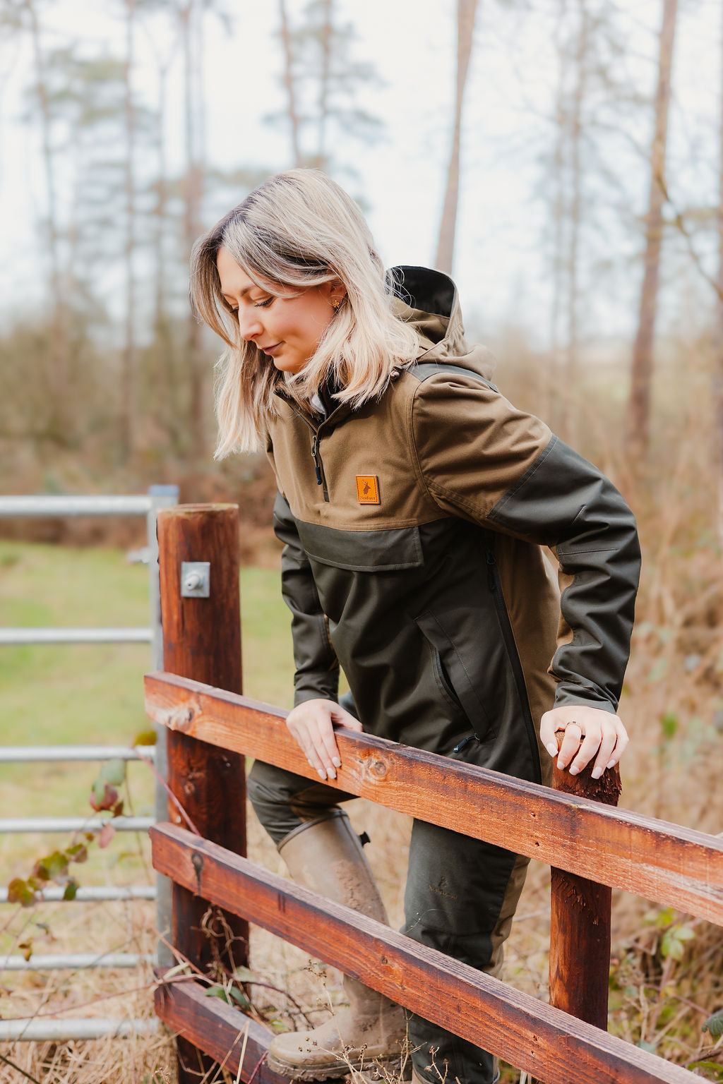 Woman in outdoor gear climbing fence wearing the Forest Nightjar Smock