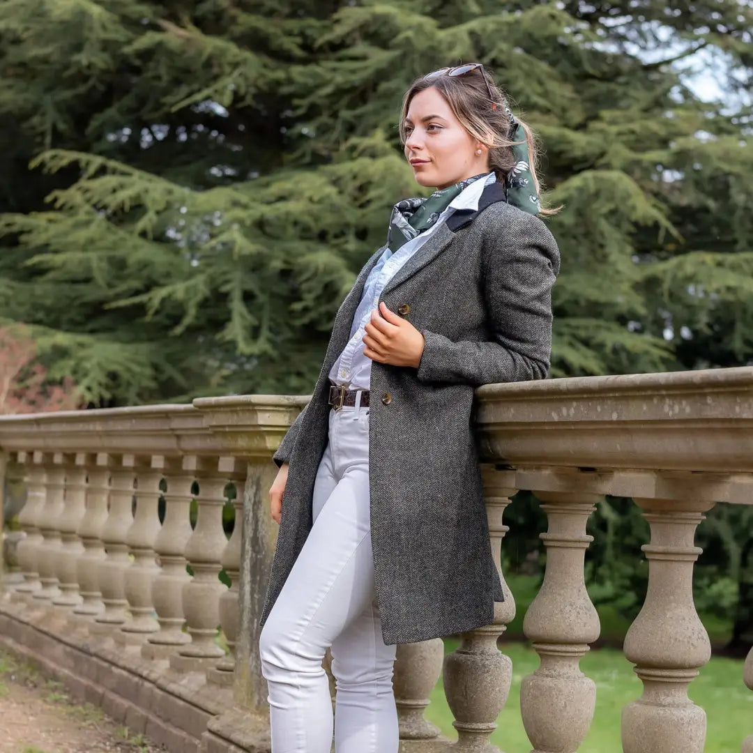 Woman in a gray Forest Lizzie Tweed Coat and white pants by a stone balustrade