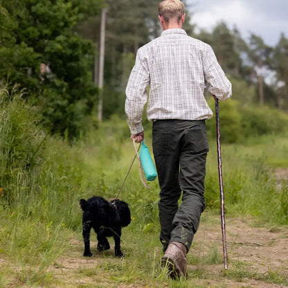 Man in Forest Moleskin Jeans walking a small black dog on a rural path