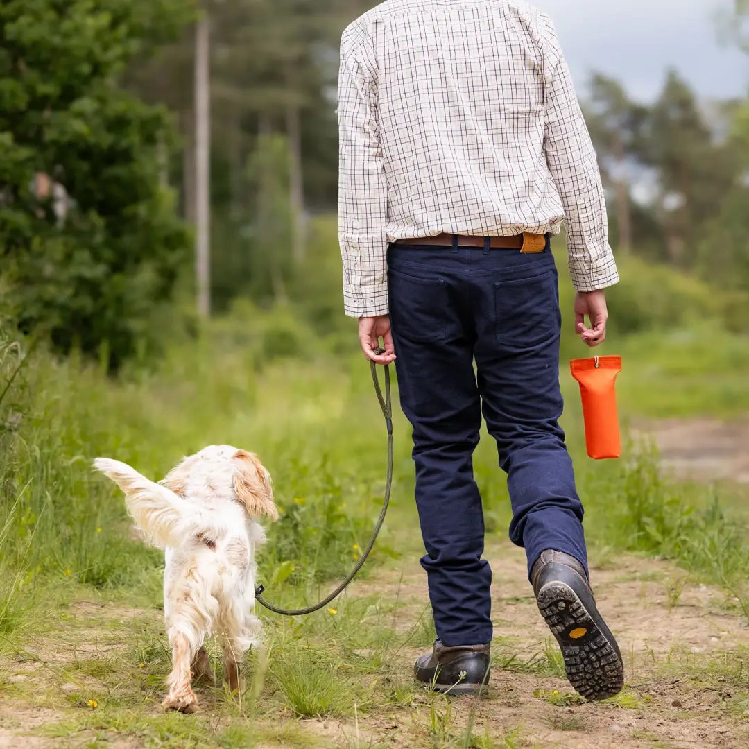 Person in Forest Moleskin Jeans walking a small white dog on a rural path