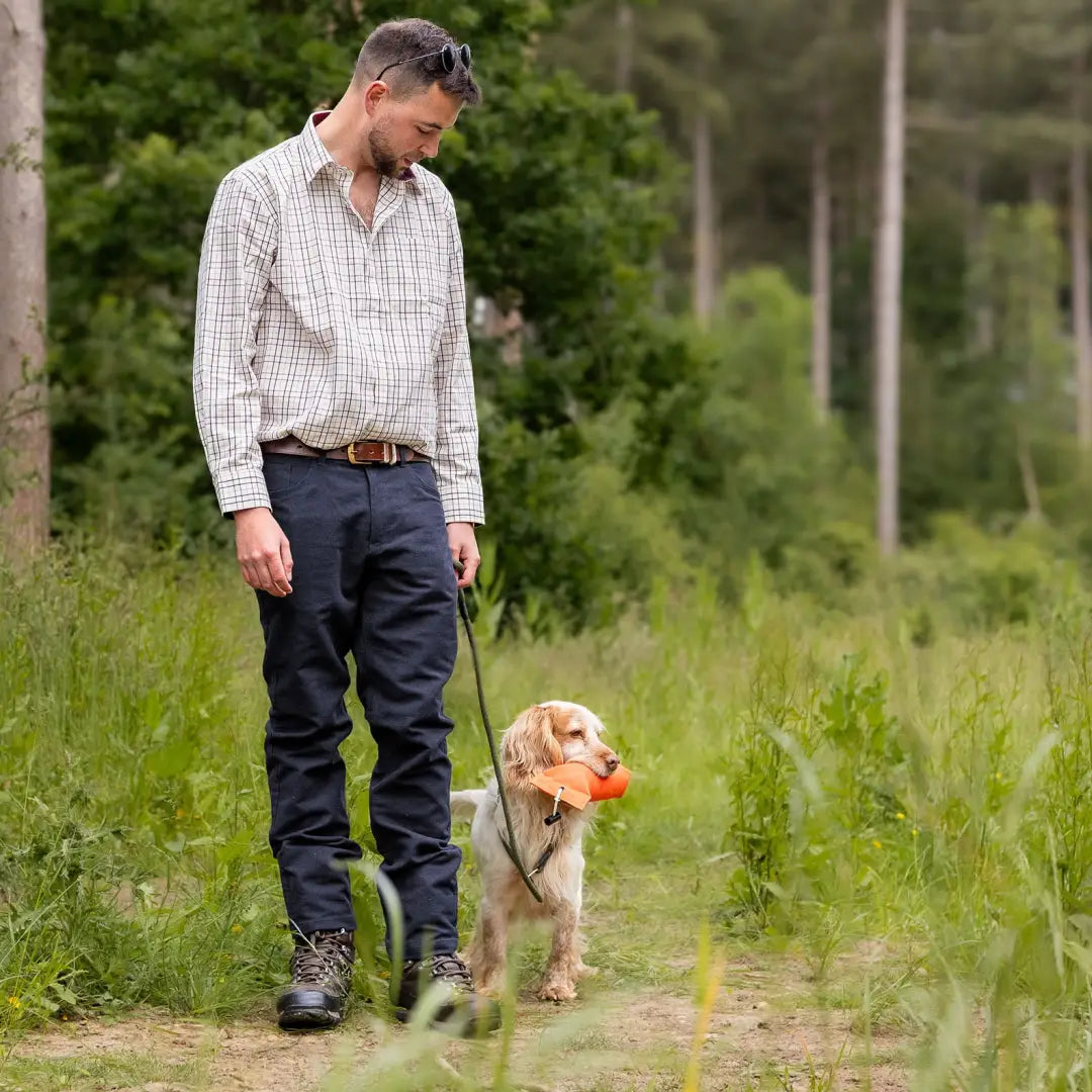 Man in Forest Moleskin Jeans walking a golden retriever in a grassy area