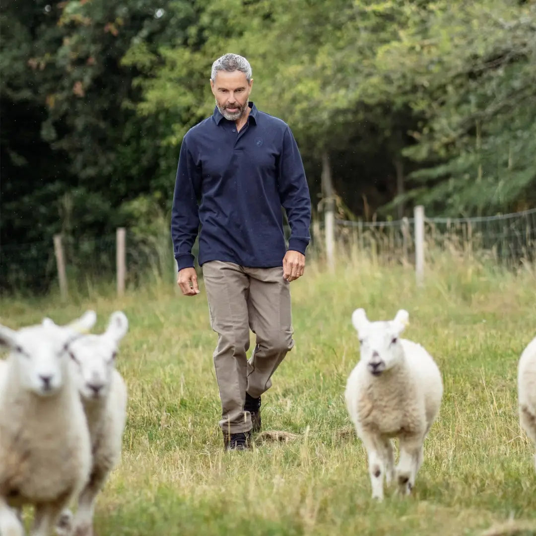 Man in New Forest Moleskin Trousers walking with sheep in a grassy field