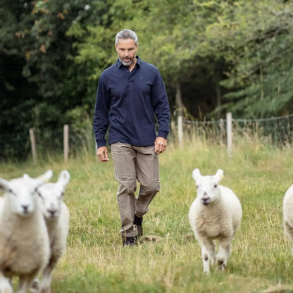 Man in New Forest Moleskin Trousers walking with sheep in a grassy field