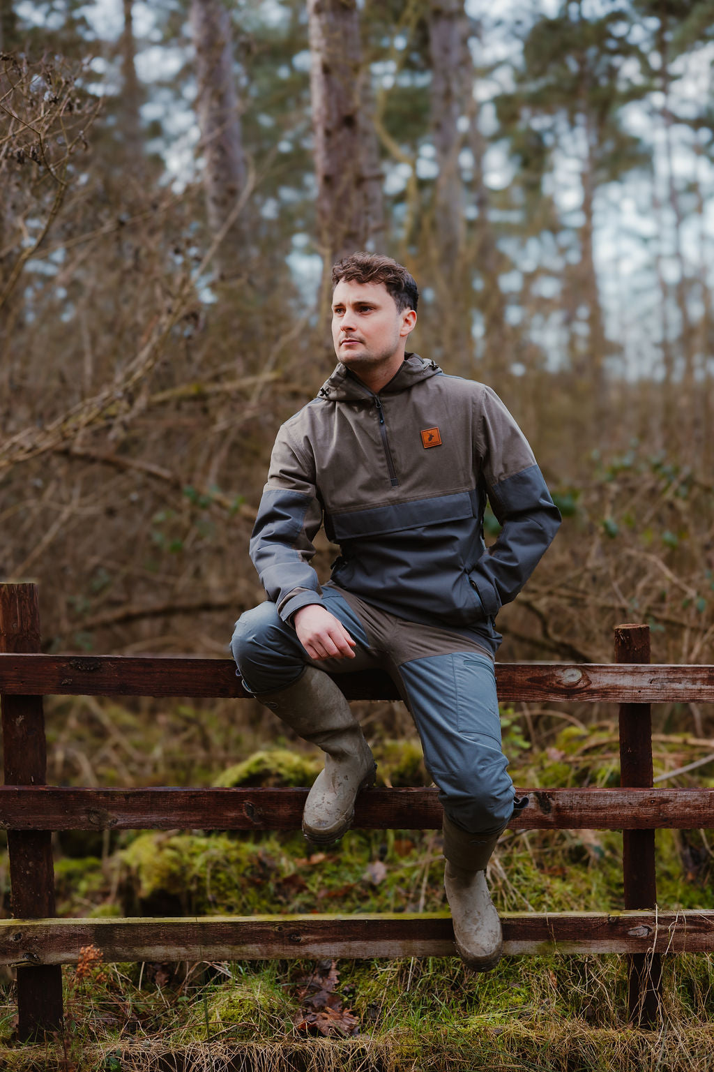 Man in outdoor clothing on a fence wearing the Forest Nightjar Smock