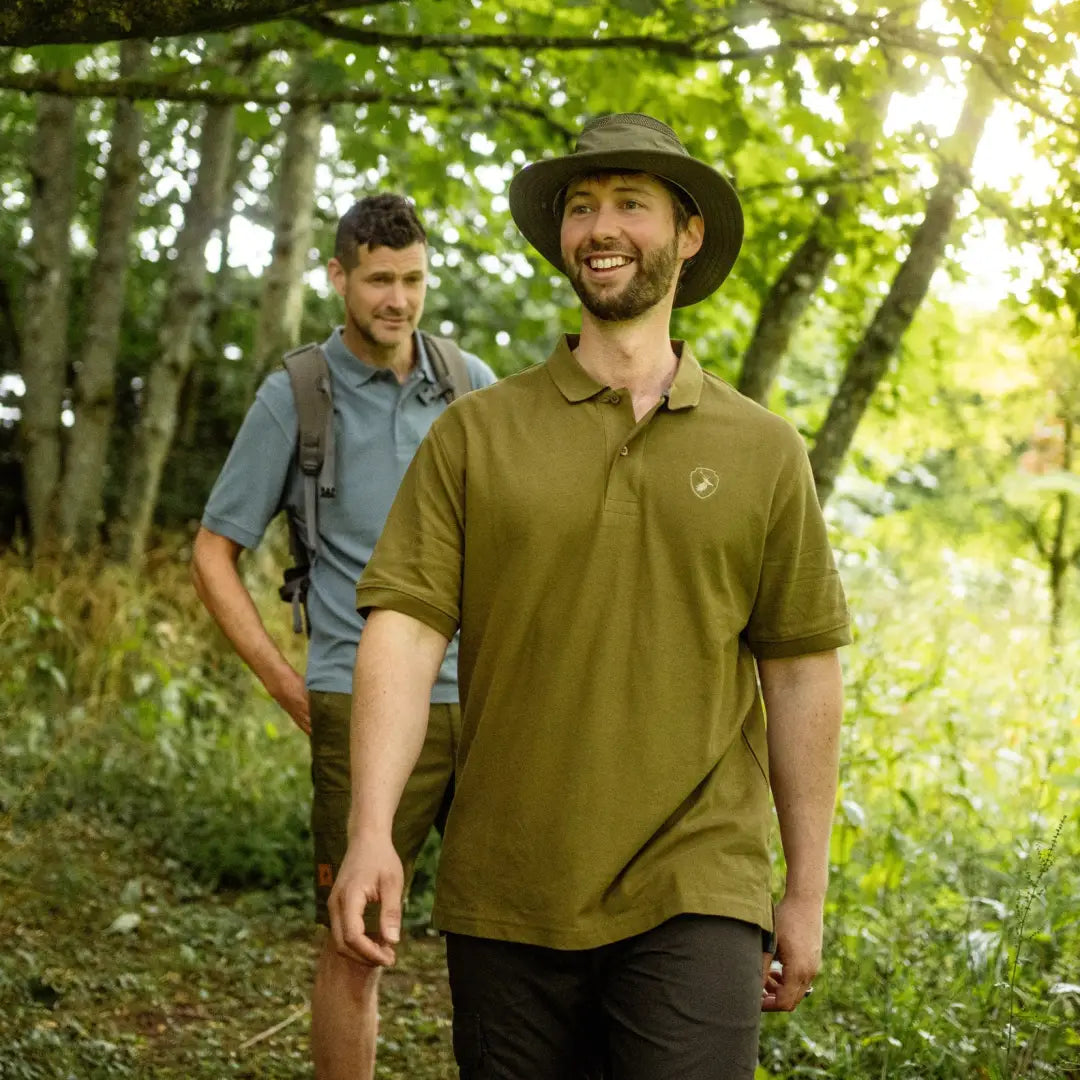 Two men hiking in a forest wearing stylish Forest Pique Polo Shirts