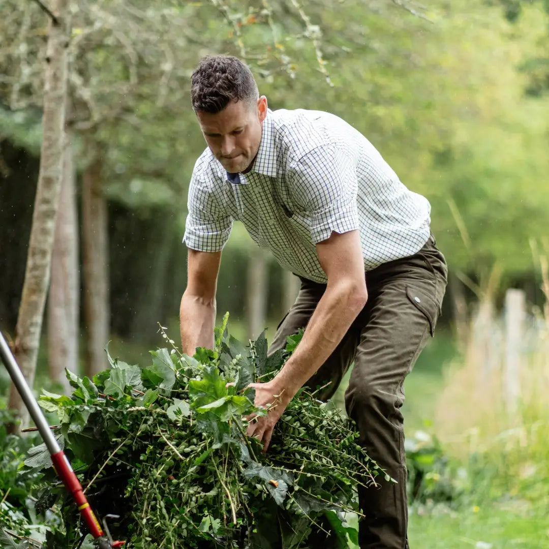 Man in a garden wearing a New Forest Premium short sleeved shirt, handling leafy plants