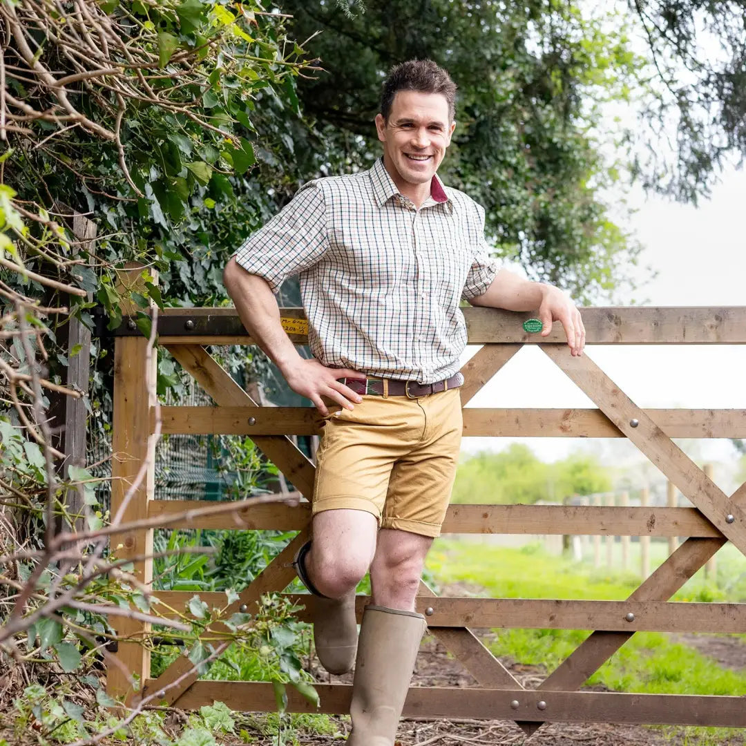 Smiling man in country clothing by a wooden gate wearing New Forest short sleeve shirt