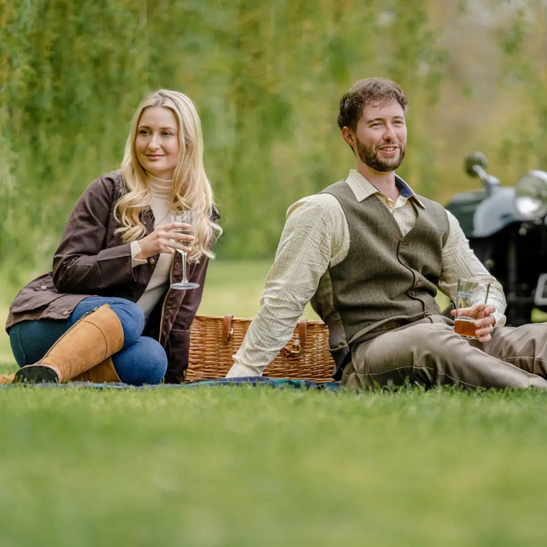 Two friends in a wool tweed waistcoat enjoying a sunny picnic on the grass