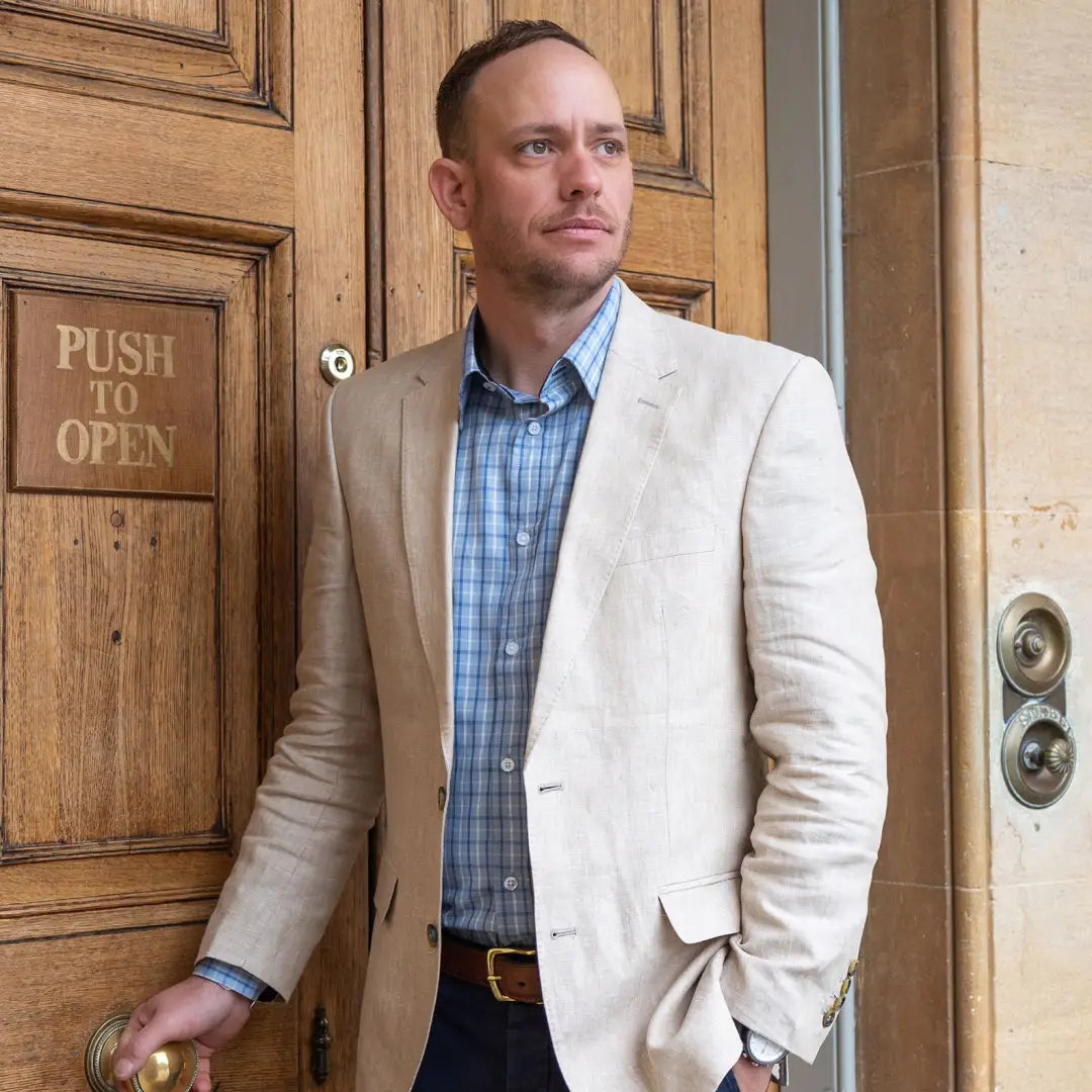 Man in light blazer and blue checked New Forest Premium Tattersall Shirt by wooden door