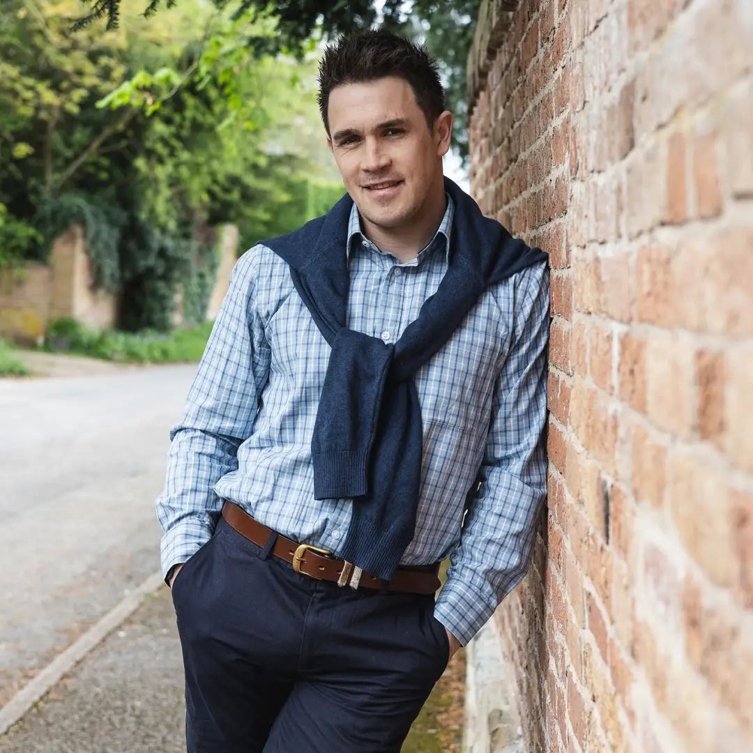 Man in a checked premium tattersall shirt with a navy sweater over his shoulders