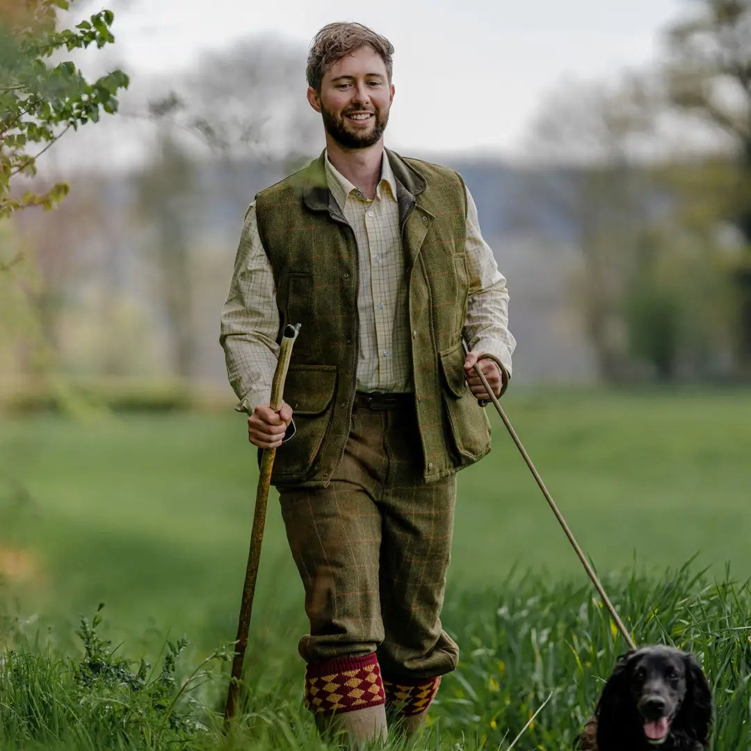 Smiling man in New Forest Premium Tattersall Shirt walking black dog in grassy field