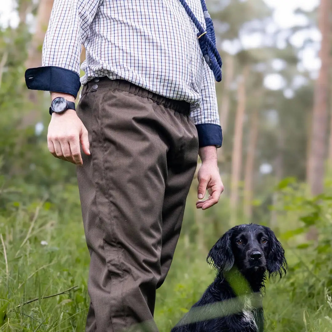 Black and white dog beside a person wearing a New Forest Premium Tattersall Shirt outdoors