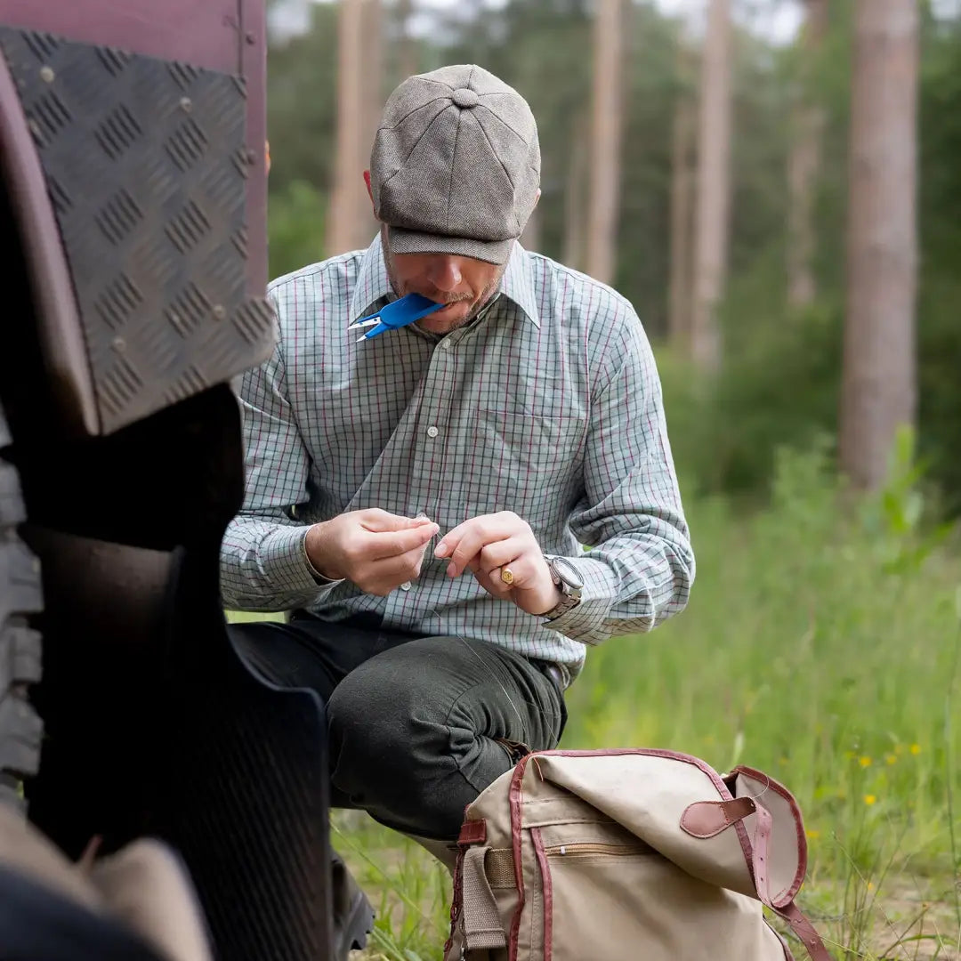 Man in a cap and plaid shirt outdoors admiring the New Forest Premium Tattersall Shirt