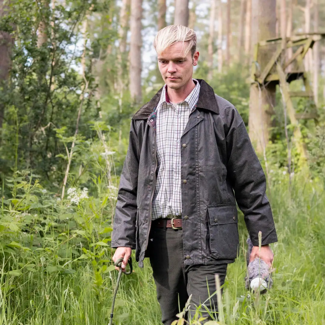 Man in dark jacket and plaid New Forest Premium Tattersall Shirt walking in tall grass