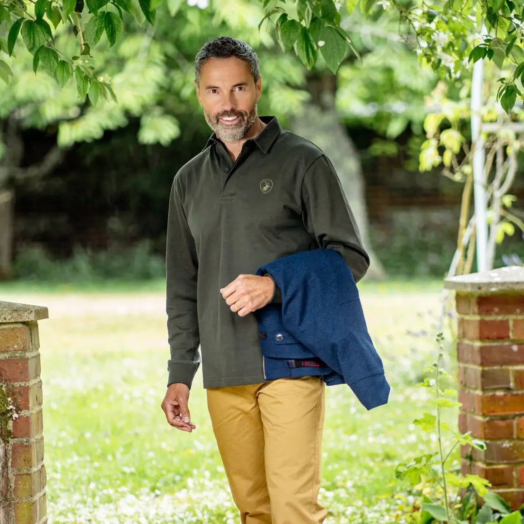 Middle-aged man in a green pullover shows off a New Forest Rugby Shirt and blue jacket