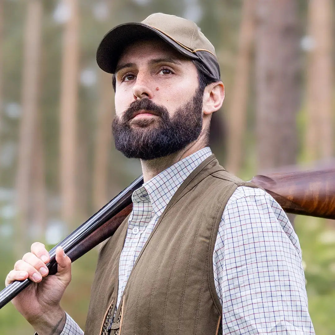 Bearded man in a cap and vest with a shotgun, showcasing the Forest Skeet Cap