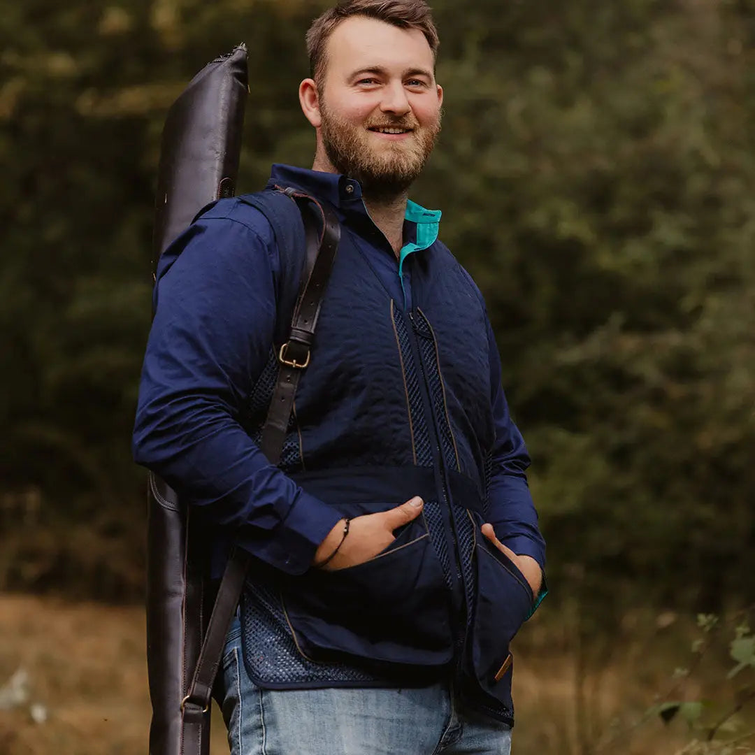 Smiling bearded man in navy blue jacket showcasing the Forest Skeet Vest outdoors