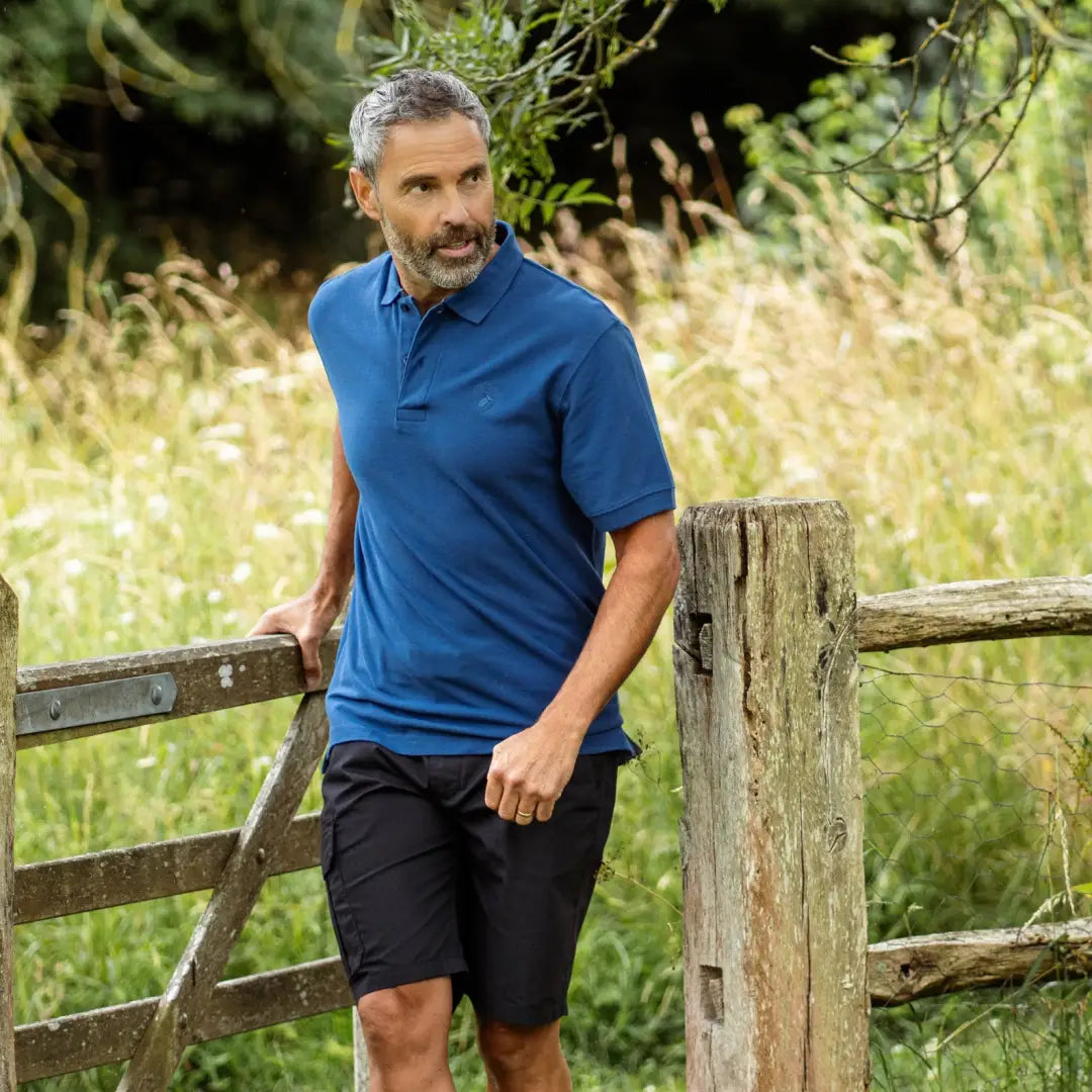 Middle-aged man sporting forest trail shorts, graying hair, and a blue polo shirt