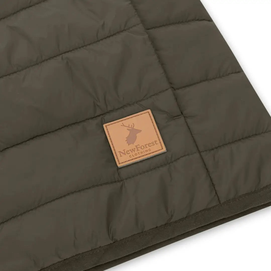 Quilted dark green fabric with a brown leather patch and deer logo on Forest Trek Jacket