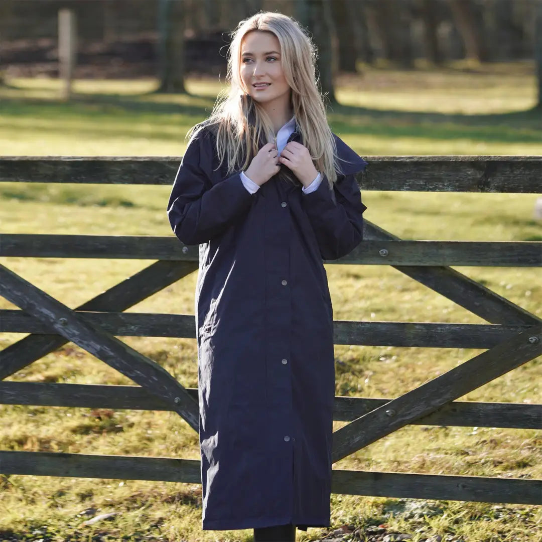 Woman in dark blue waterproof coat by a wooden fence, showing off the New Forest Victoria style