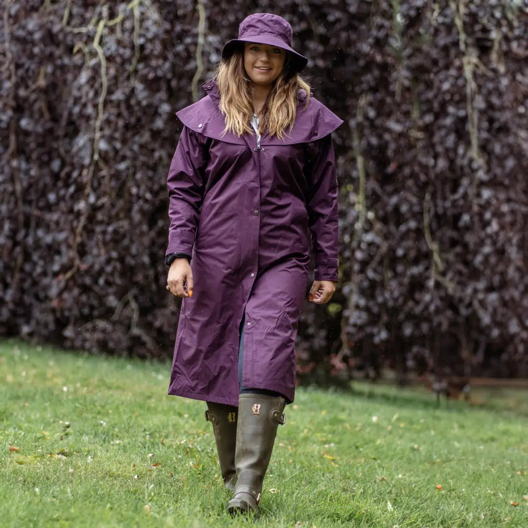 Purple raincoat and hat on a person walking grass, perfect for uncompromising wet weather