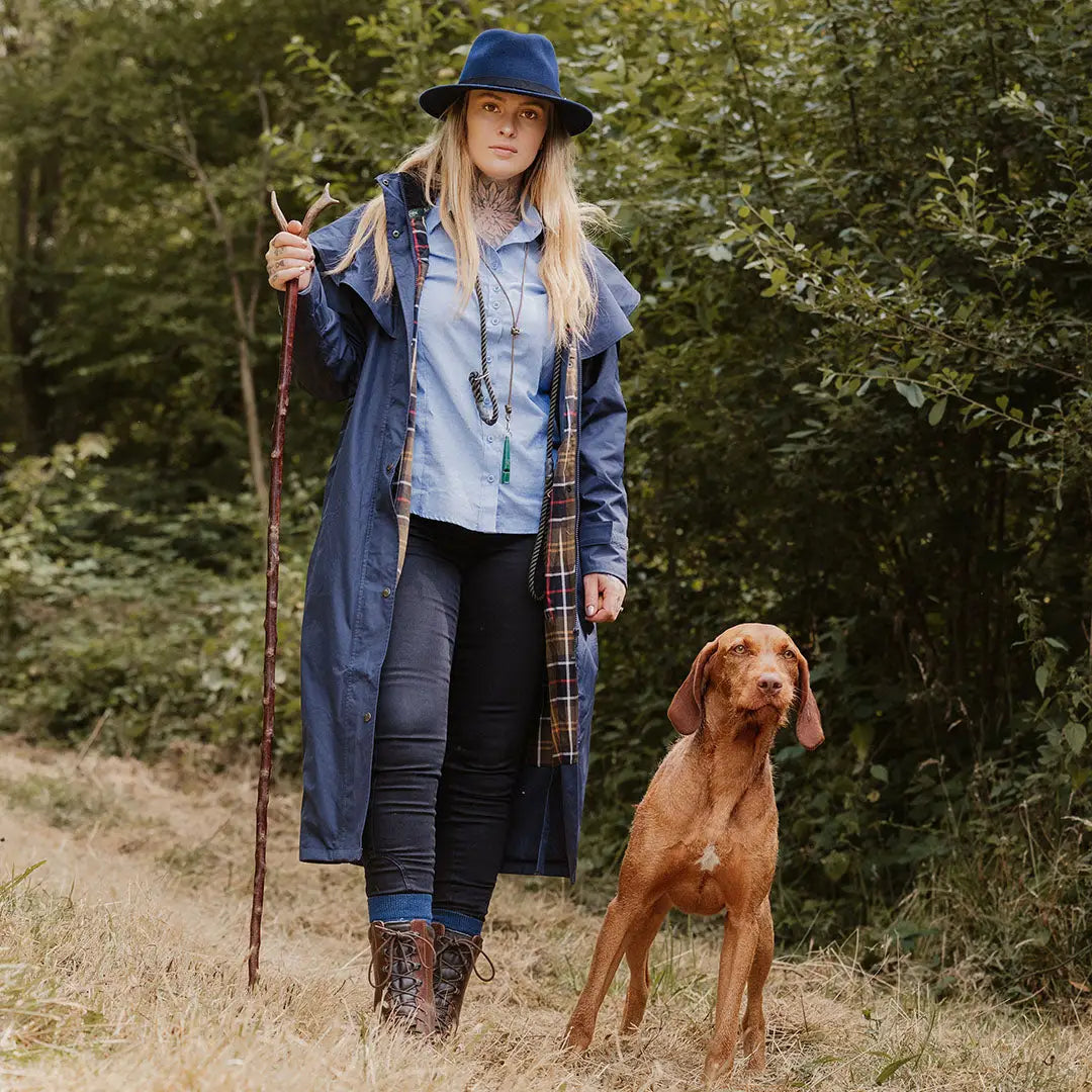 Woman in a blue hat and coat with brown dog on path by New Forest Victoria Waterproof Coat