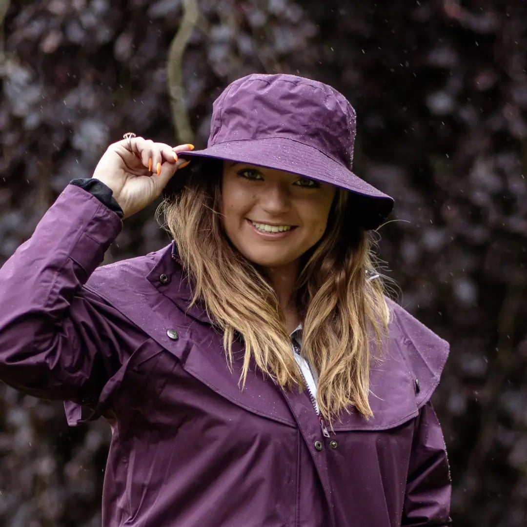 Smiling person in a Purple Rain Victoria Hat made with outer waterproof fabric