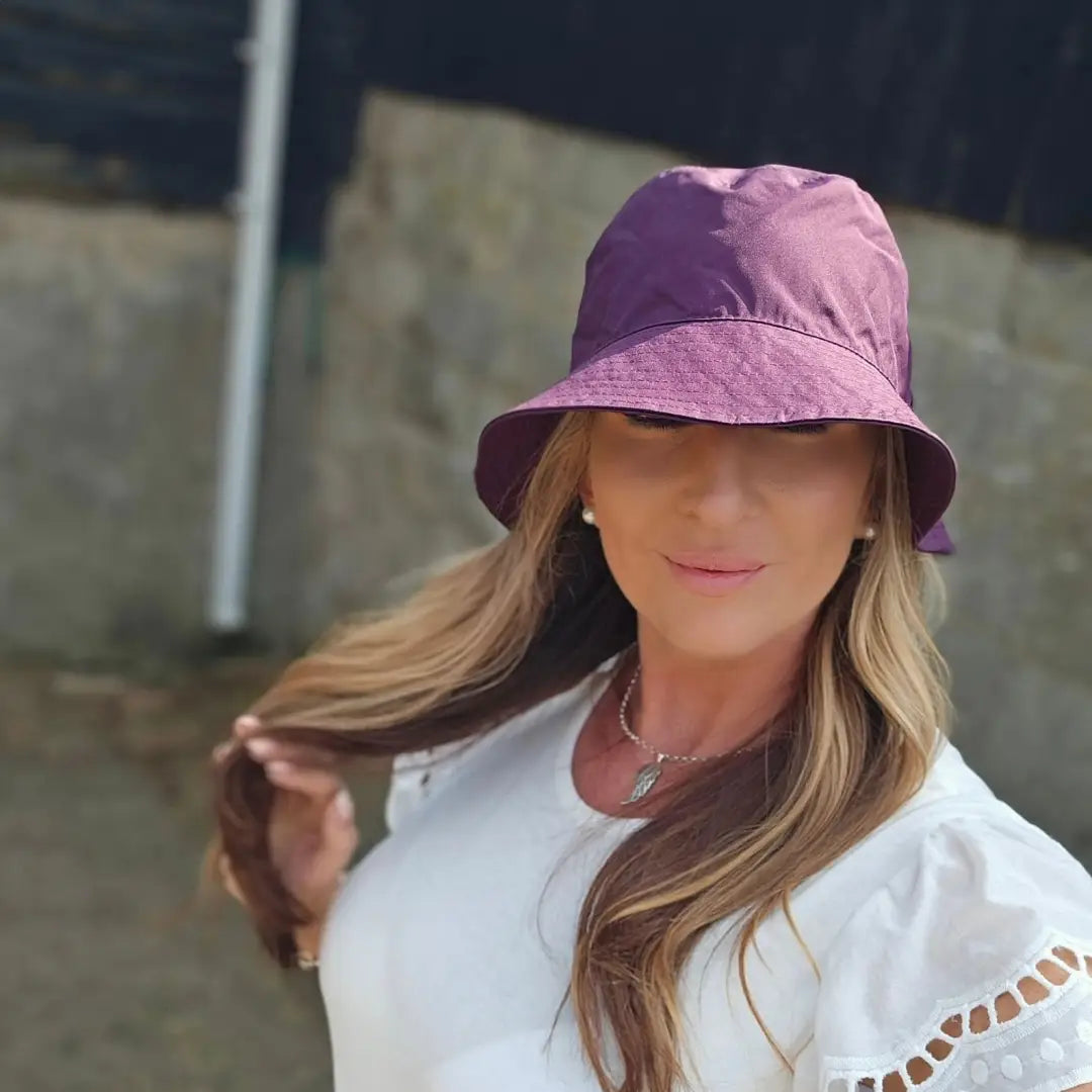 Person with long blonde hair sporting a Purple Victoria Hat made from outer waterproof fabric