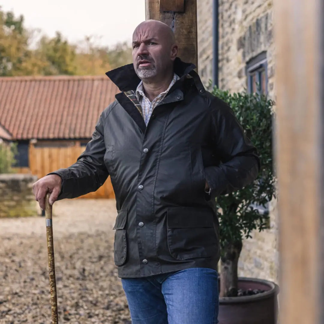 Middle-aged man in a dark jacket holding a stick, showcasing the Forest Woodsman Wax Jacket