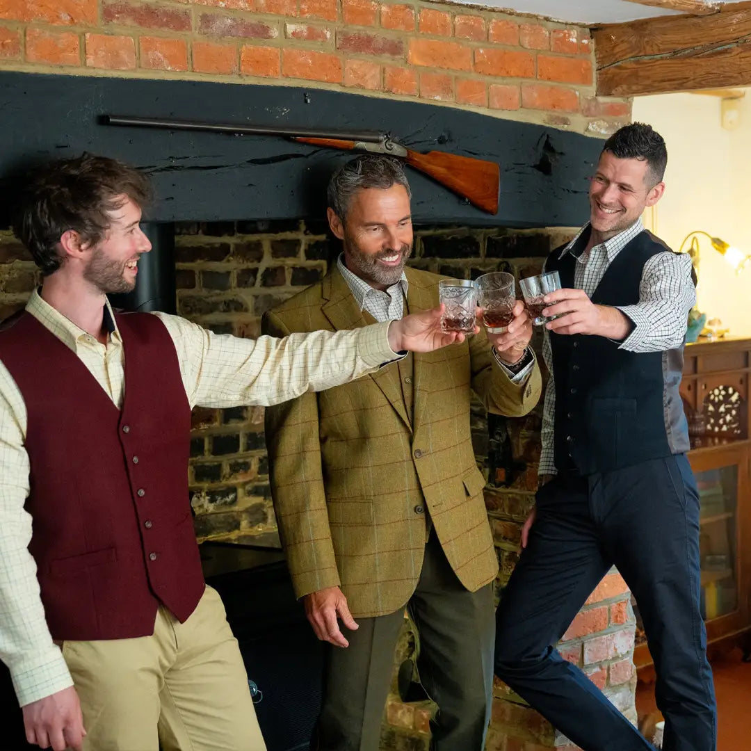 Three men toasting with glasses of whiskey in stylish wool mix waistcoat