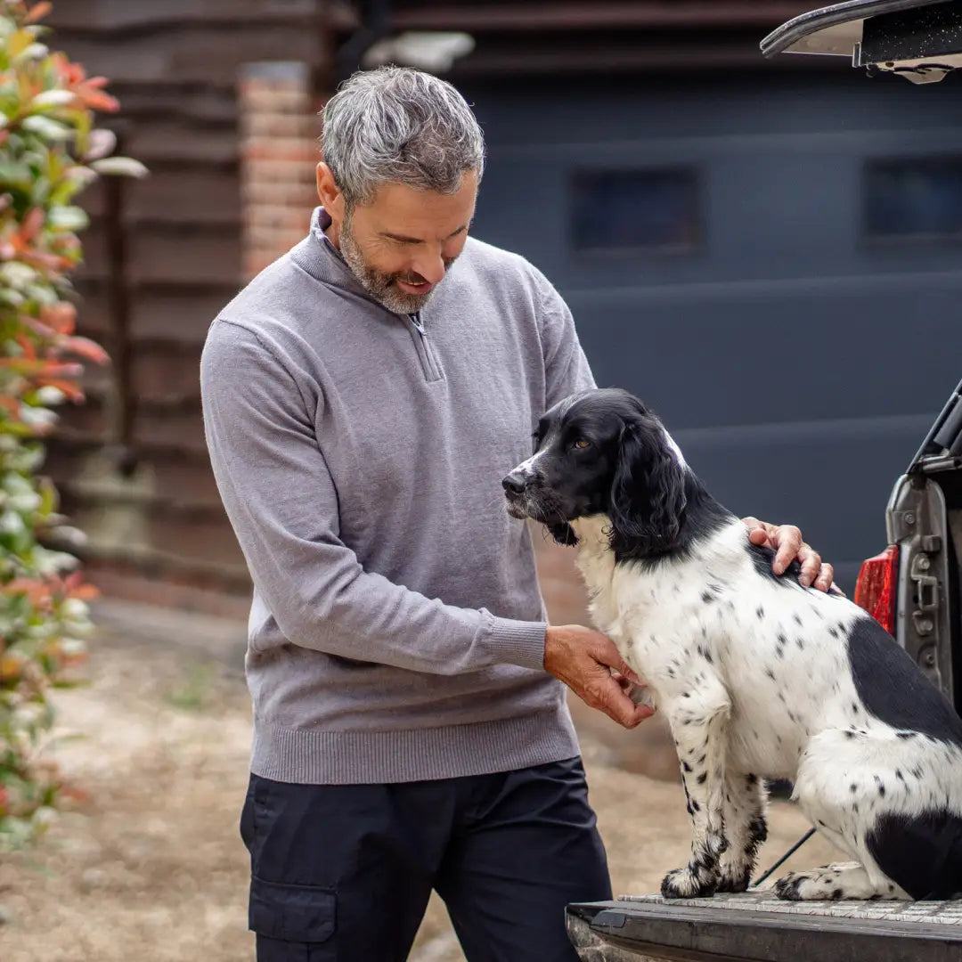 Man petting a black and white spotted dog while wearing a comfy zip neck jumper