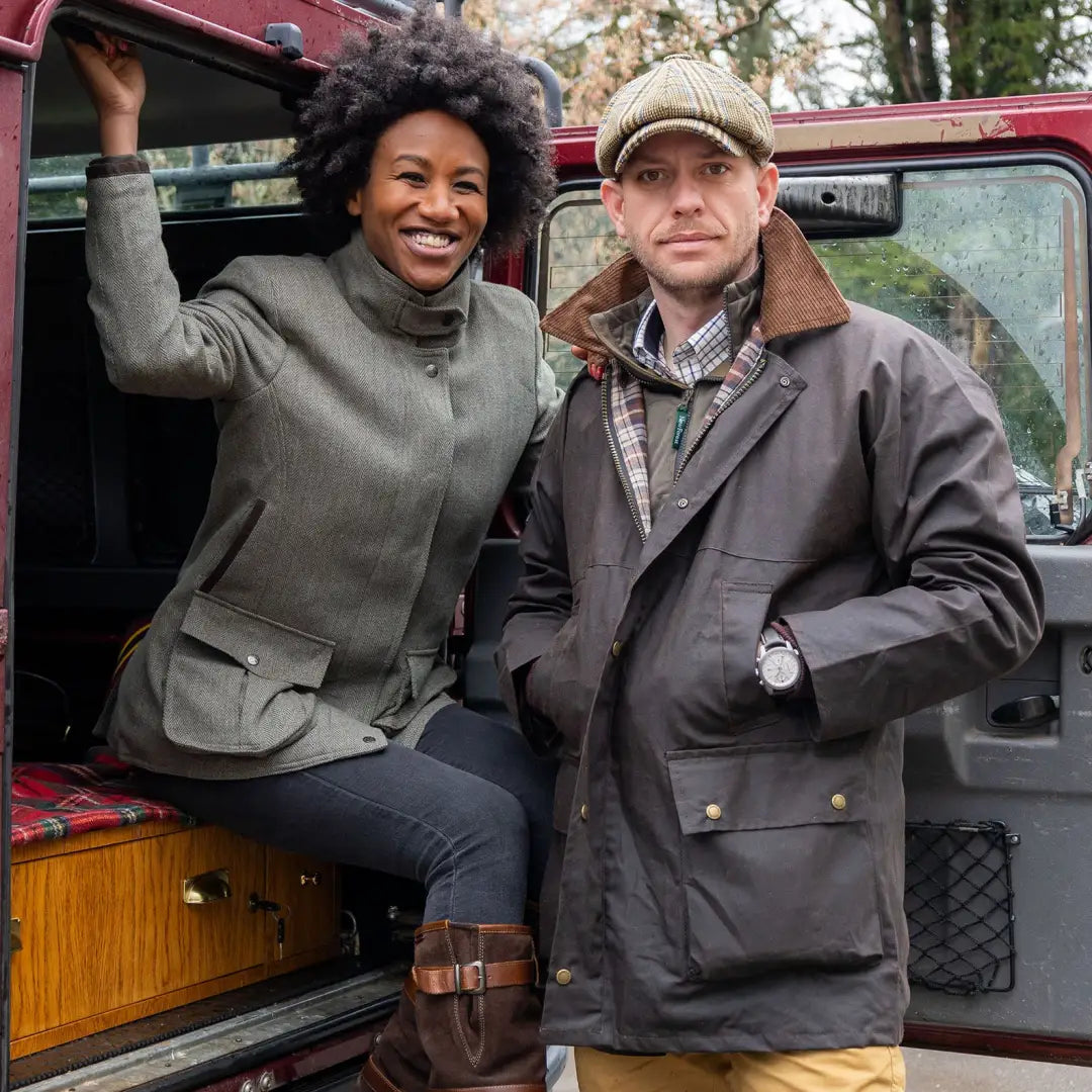 People in a padded wax jacket by a vintage Land Rover, perfect for forest clothing vibes