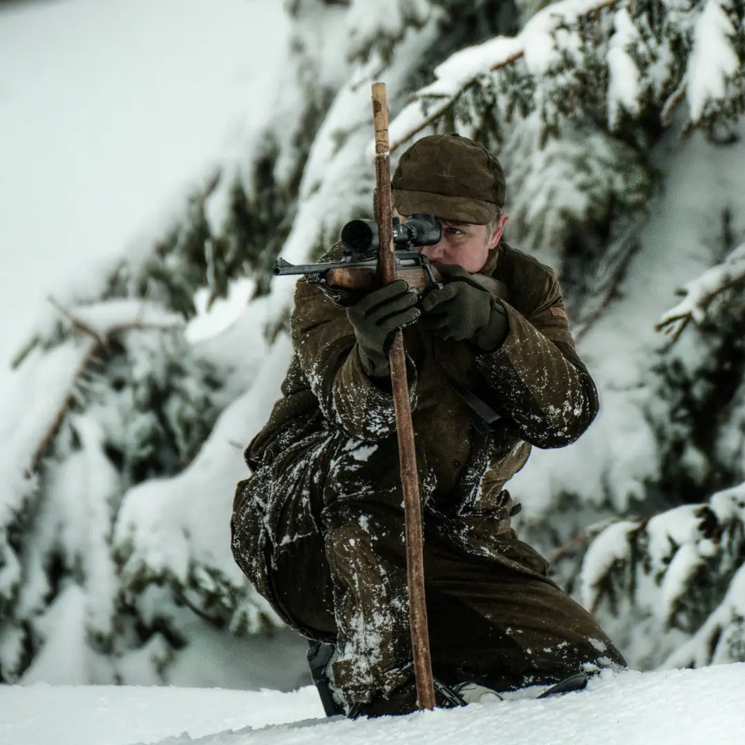 Hunter wearing Percussion Grand Nord Jacket kneeling in snow, aiming a rifle