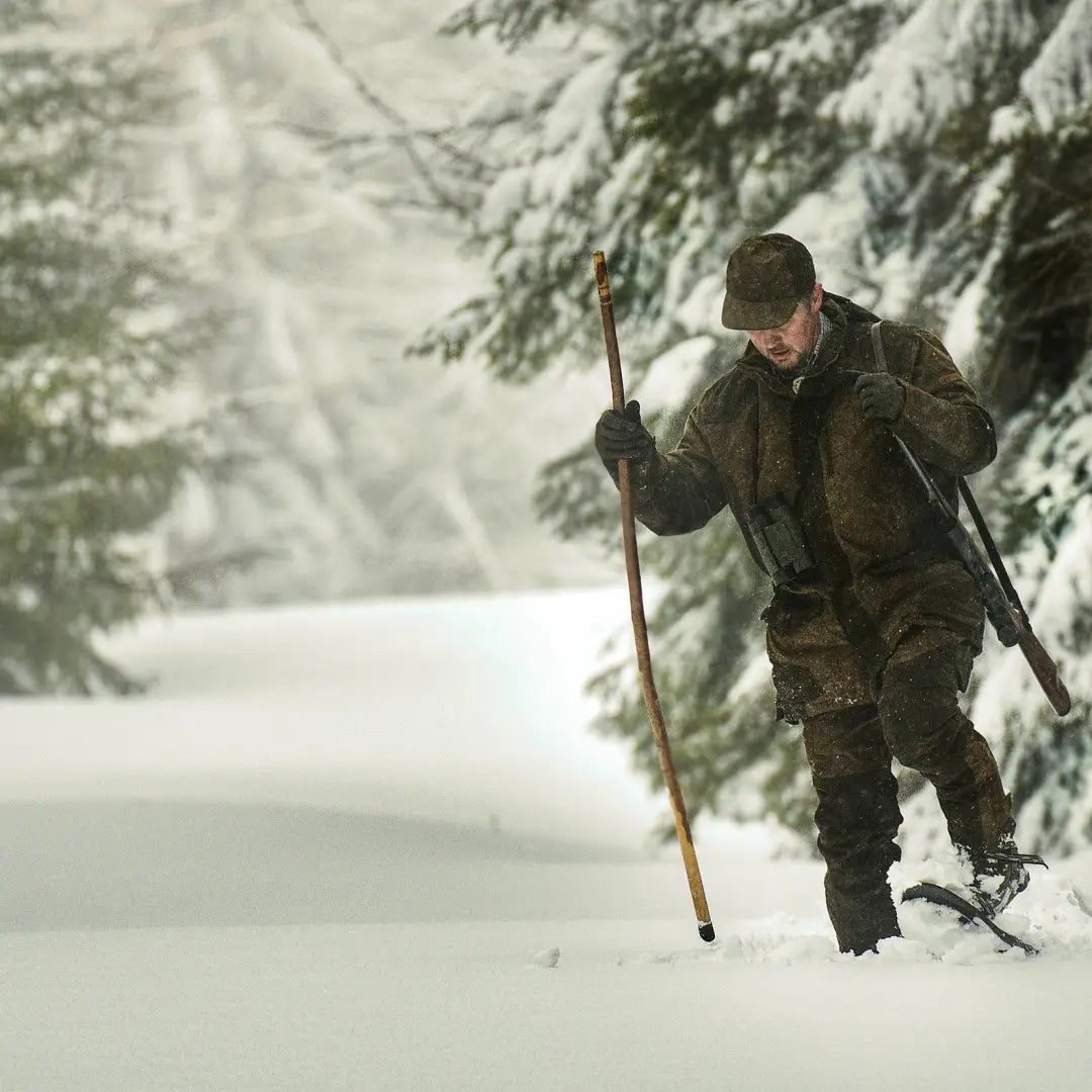 Hunter on snowshoes in deep snow wearing Percussion Grand Nord Trousers in winter forest