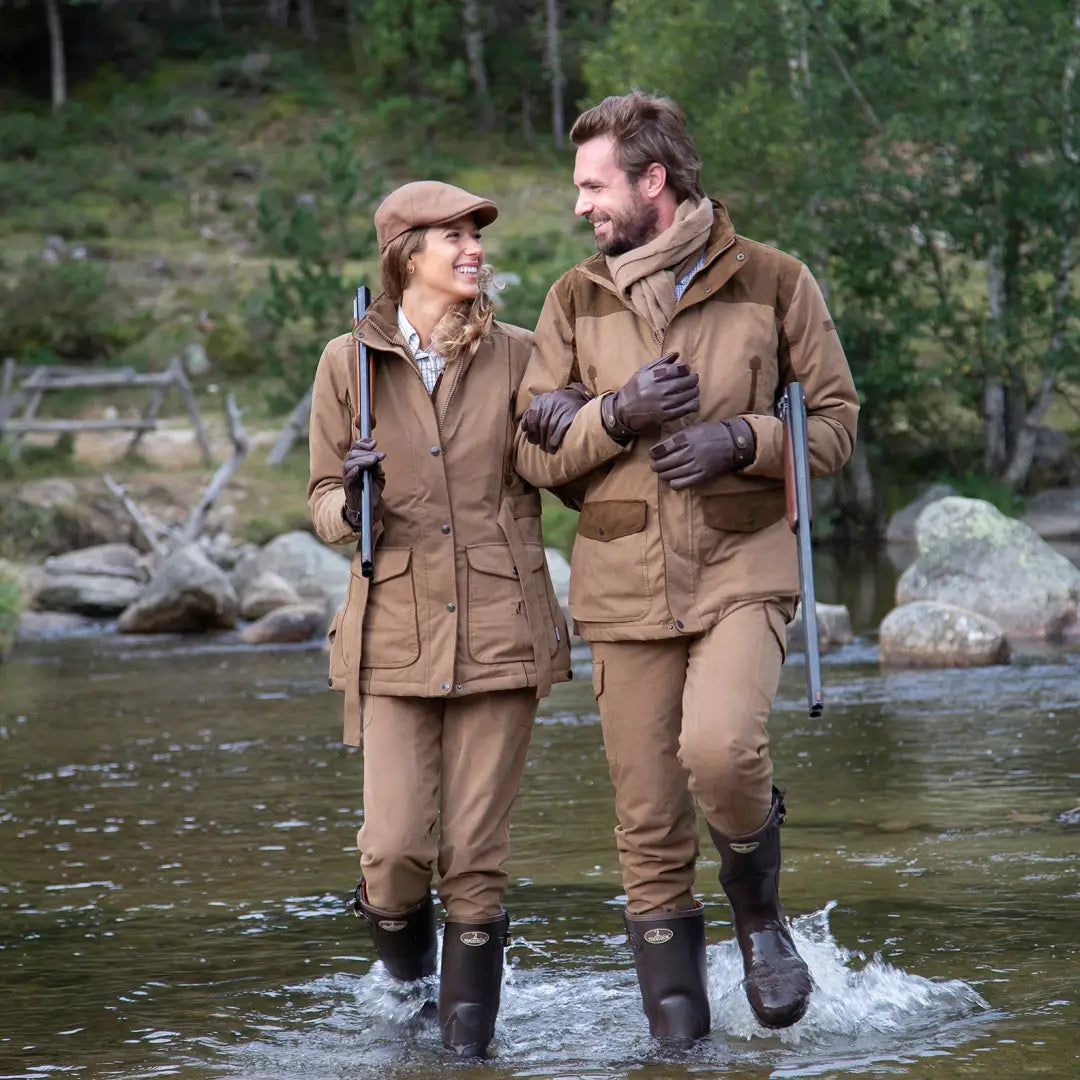 Couple in outdoor gear wading through stream, showcasing Percussion Rambouillet trousers